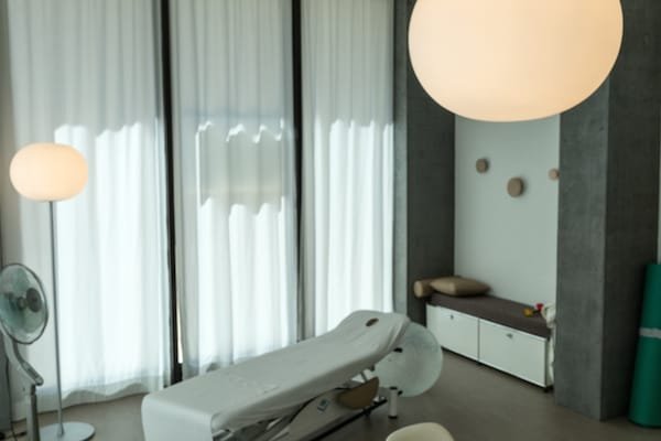 Behandlungsraum mit Liege und Wandgarderobe in ruhigem Licht.
